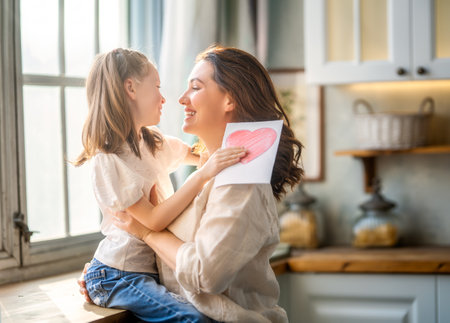 Happy mother's day. Child daughter congratulating her mother and giving her postcard.の写真素材