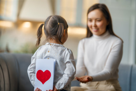 Happy mother's day. Child daughter congratulating her mother and giving her postcard.の写真素材