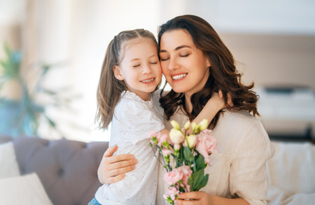 Happy mother's day. Child daughter congratulating her mother and giving her bouquet of flowers.の写真素材