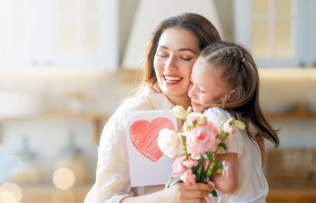 Happy mother's day. Child daughter congratulating her mother and giving her bouquet of flowers.の写真素材
