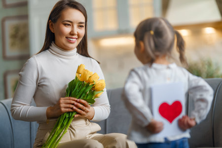 Happy mother's day. Child daughter congratulating her mother and giving her bouquet of flowers.の写真素材
