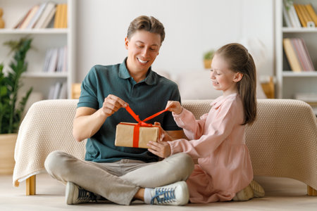 Happy father's day! Child daughter congratulating dad and giving him gift box. Daddy and girl smiling and hugging. Family holiday and togetherness.の写真素材