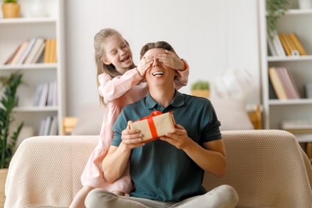 Happy father's day! Child daughter congratulating dad and giving him gift box. Daddy and girl smiling and hugging. Family holiday and togetherness.の写真素材