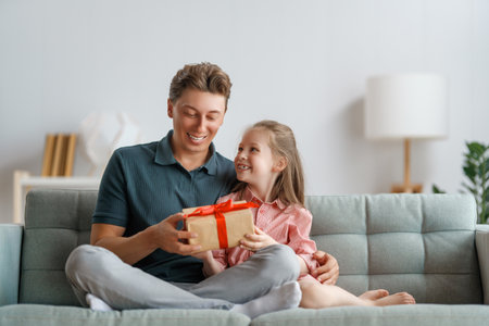 Happy father's day! Child daughter congratulating dad and giving him gift box. Daddy and girl smiling and hugging. Family holiday and togetherness.の写真素材