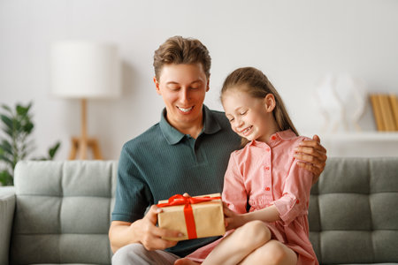 Happy father's day! Child daughter congratulating dad and giving him gift box. Daddy and girl smiling and hugging. Family holiday and togetherness.の写真素材