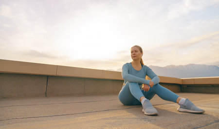 Young sportswoman is warming up, training or doing stretch exercise on rooftop of parking, garage in summer day morning.の写真素材