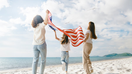 Patriotic holiday. Happy family, mom and daughters children girls with American flag outdoors. The USA celebrate 4th of July.の写真素材