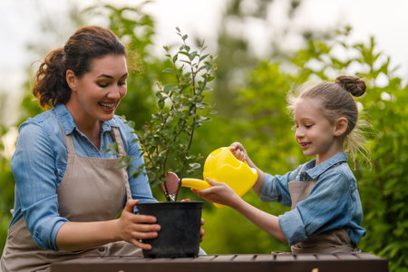 Happy mother and daughter gardening in the backyard. Kid helping her mom and learning botany.の写真素材