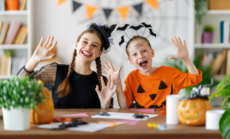Happy family preparing for Halloween. Cute children in carnival costumes carving pumpkins at home.の写真素材