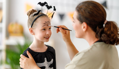 Happy family preparing for Halloween. Mother and child in carnival costume at home.の写真素材