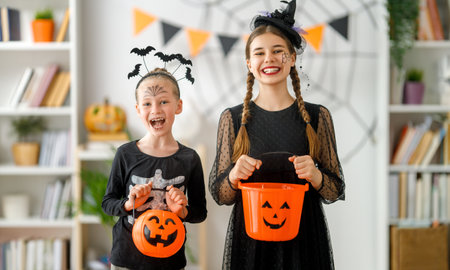 Cute little children girls in carnival costumes. Happy family preparing for Halloween. Funny kids at home.の写真素材