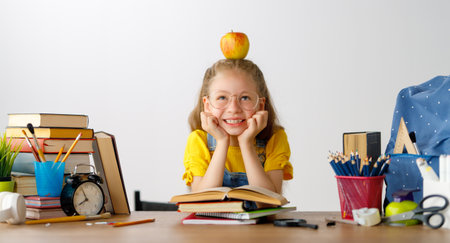 Back to school! Happy cute industrious child is sitting at a desk indoors. Kid is learning in class or lesson.の写真素材