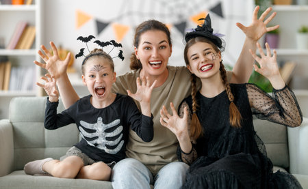 Happy family preparing for Halloween. Mother and children in carnival costumes at home.の写真素材