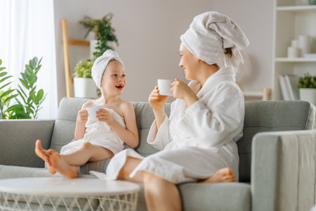 Happy family. Mother and daughter child girl are drinking tea after a bath.の写真素材