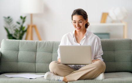 Happy woman studying online, watching webinar, podcast on laptop, making notes. E-learning concept.の写真素材