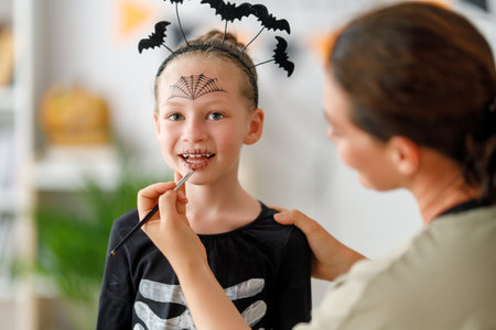 Happy family preparing for Halloween. Mother and child in carnival costume at home.の写真素材