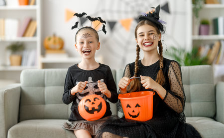 Happy family celebrating Halloween. Cute children in carnival costumes with carving pumpkins at home.の写真素材