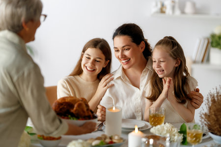 Thanksgiving Day, Autumn feast. Happy family sitting at the table and celebrating holiday. Traditional dinner. Grandmother, mother and daughters.の写真素材