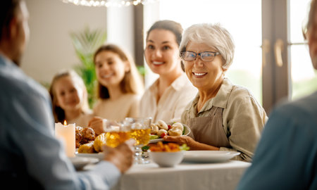 Thanksgiving Day, Autumn feast. Happy family sitting at the table and celebrating holiday. Grandparents, mother, father and children. Traditional dinner.の写真素材