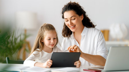Back to school. Happy child and adult are sitting at desk. Girl doing homework or online education.の写真素材