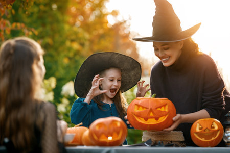 Happy family preparing for Halloween. Mother and children carving pumpkins in the backyard of the house.の写真素材