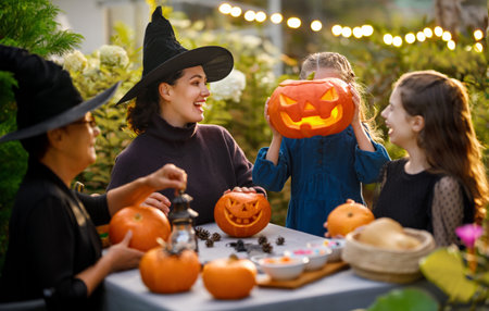 Happy family preparing for Halloween. Mother, grandmother and children carving pumpkins in the backyard of the house.の写真素材
