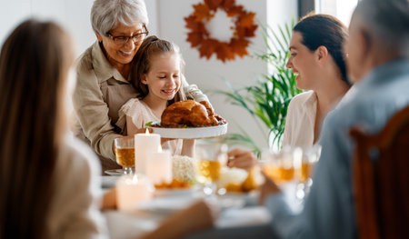 Thanksgiving Day, Autumn feast. Happy family sitting at the table and celebrating holiday. Grandparents, mother and children. Traditional dinner.の写真素材