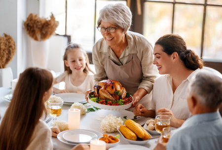 Thanksgiving Day, Autumn feast. Happy family sitting at the table and celebrating holiday. Grandparents, mother and children. Traditional dinner.の写真素材