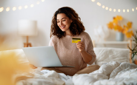 Woman is doing online purchases. Girl is doing shopping using laptop and credit card at home.の写真素材