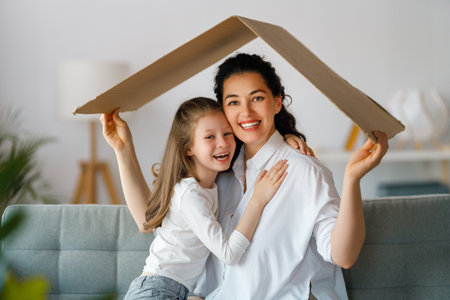 Mother and child girl in the room with a symbol of roof. Concept of housing for young family.の写真素材
