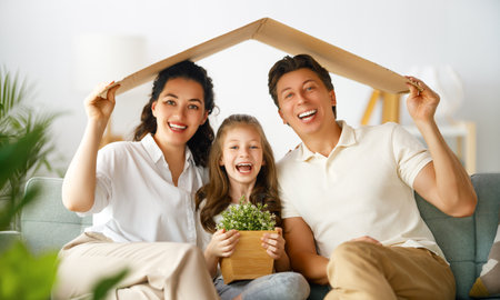 Mother, father and child girl in the room with a symbol of roof. Concept of housing for young family.の写真素材