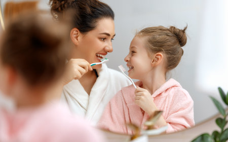 Happy family! Mother and daughter child girl are brushing teeth toothbrushes in the bathroom.の写真素材
