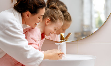 Cute little girl and her mother are washing hands under running water.の写真素材