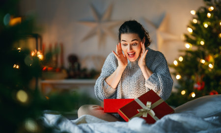 Merry Christmas, Happy Holidays. Surprised happy woman opening a Christmas present.の写真素材