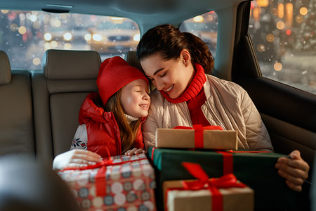 Woman and her child  holding presents and delivering them on car to home. Holidays concept. Time of Christmas Eve.の写真素材