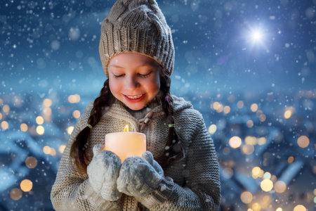 Adorable little girl with candle on Christmas outdoors.の写真素材