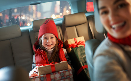Woman and her child  holding presents and delivering them on car to home. Holidays concept. Time of Christmas Eve.の写真素材