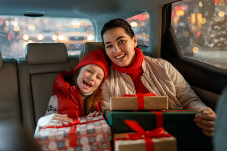 Woman and her child  holding presents and delivering them on car to home. Holidays concept. Time of Christmas Eve.の写真素材
