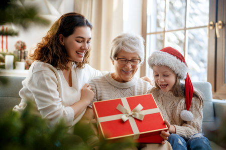 Merry Christmas and Happy Holidays. Cheerful kid presenting gifts to mom and granny. Parents and little child having fun near tree indoors. Loving family with presents in room.の写真素材