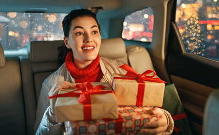 Woman is  holding presents and delivering them on car to home. Holidays concept. Time of Christmas Eve.の写真素材