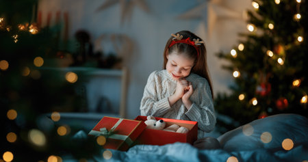Merry Christmas and Happy Holidays. Cheerful cute child girl with gift. Kid is having fun near tree.の写真素材