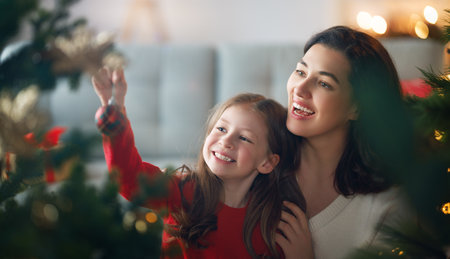 Merry Christmas, Happy Holidays. Mom and daughter near the tree indoors. The morning before Xmas.の写真素材
