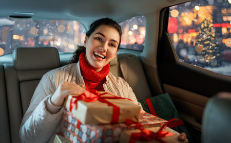 Woman is  holding presents and delivering them on car to home. Holidays concept. Time of Christmas Eve.の写真素材