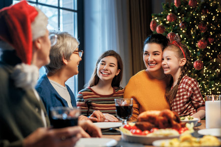 Merry Christmas! Happy family are having dinner at home. Celebration holiday and togetherness near tree.の写真素材