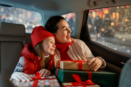 Woman and her child  holding presents and delivering them on car to home. Holidays concept. Time of Christmas Eve.の写真素材