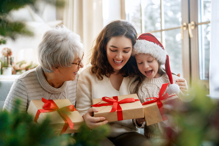 Merry Christmas and Happy Holidays. Cheerful kid presenting gifts to mom and granny. Parents and little child having fun near tree indoors. Loving family with presents in room.の写真素材