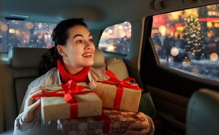 Woman is  holding presents and delivering them on car to home. Holidays concept. Time of Christmas Eve.の写真素材