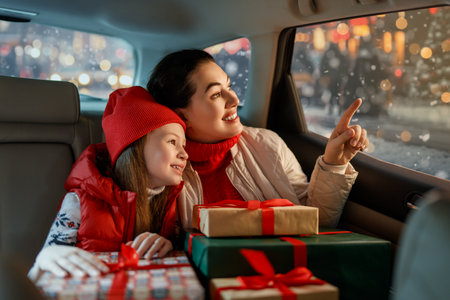 Woman and her child  holding presents and delivering them on car to home. Holidays concept. Time of Christmas Eve.の写真素材
