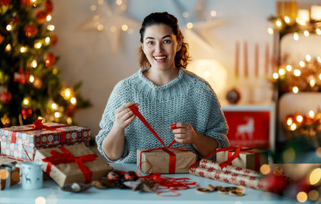 Merry Christmas and Happy Holidays. Cheerful pretty young woman preparing  presents.の写真素材
