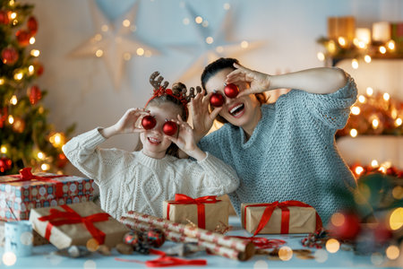 Happy Holidays. Cheerful mother and her cute daughter girl preparing for Christmas. People wrapping gifts, decorating home. Loving family with presents in room.の写真素材